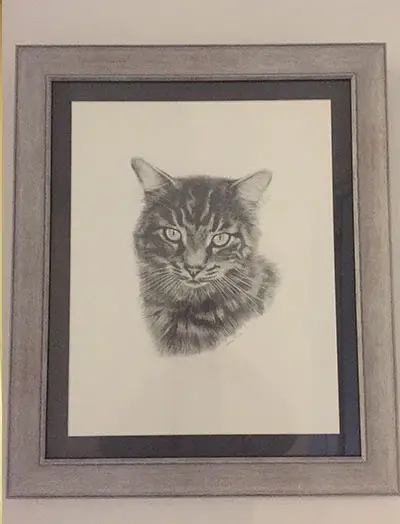 Client Rachel holding her new pet portrait of Jet, admiring its amazing quality and how it captures everything about him.