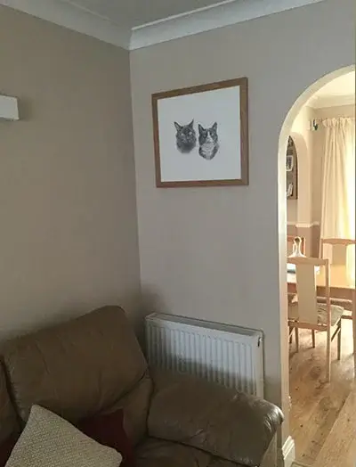 A framed cat portrait displayed prominently on a wall in a client's home, chosen for its significant size.